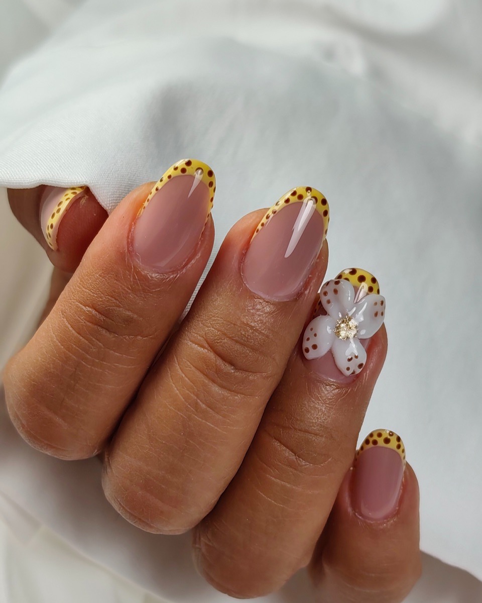 Uñas con puntas amarillas y una flor pintada a mano